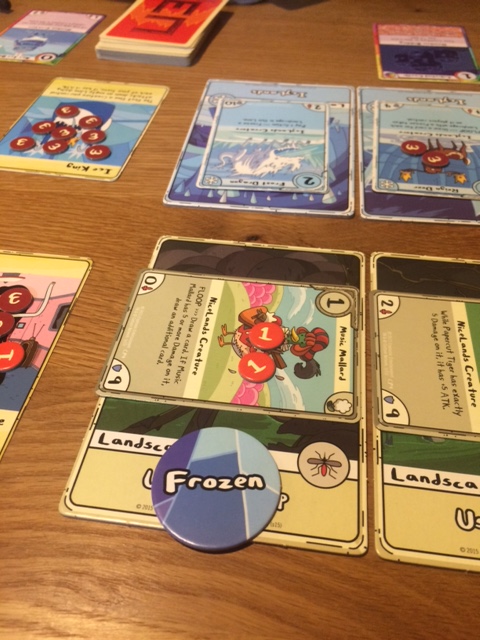 Mon adversaire bloque mon Canard musicien, très utile parce qu'il me permet de piocher des cartes gratuitement. Les jetons "Frozen" sont essentiels à sa victoire. Ils permettent de bloquer les créatures posées sur les lieux, et de me forcer à jeter des cartes pour les enlever et réactiver mes créatures.